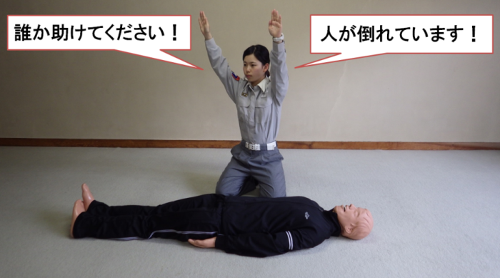 傷病者の傍で救助者が大声で周りに助けを求めている様子の写真。救助者が両手を挙げて「誰か助けて下さい!人が倒れています」と呼びかけている。