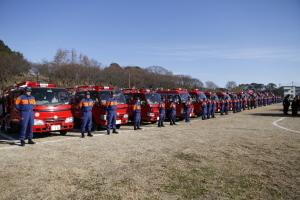出初式において並べられた消防車とその前で整列する隊員たちの写真
