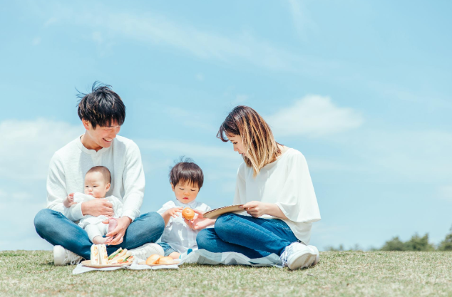 父母とこどもが芝生で談笑している