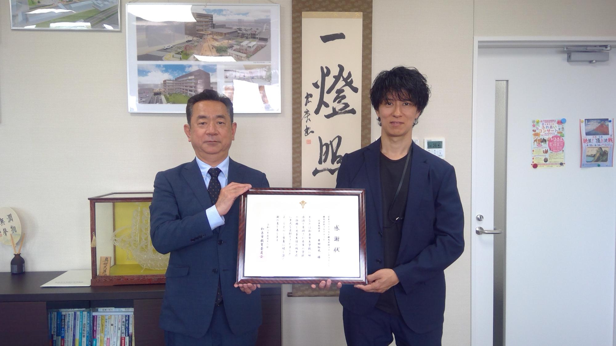 大槻教育長がマクドナルド株式会社フランチャイジー 株式会社フルグラッド 代表取締役 半田裕也様へ感謝状を渡している写真