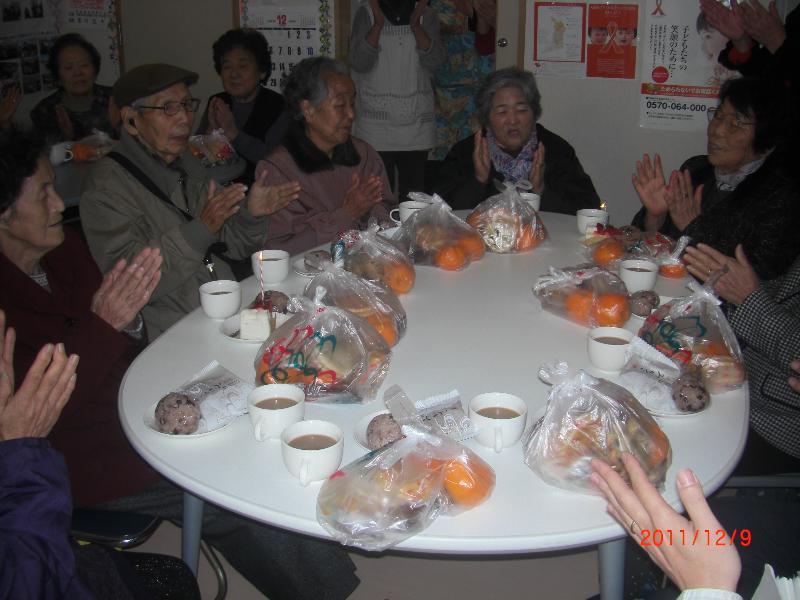 ごちそうを並べたテーブルを囲んで誕生日をお祝いする参加者たちの写真