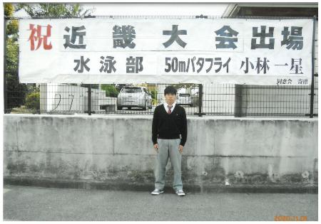 近畿大会出場を祝う横断幕の前に立つ小林いっせいさん
