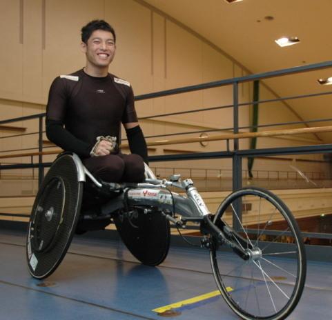 マラソン競技用車椅子に乗って撮影に応じる西田宗城さんの写真