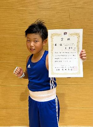 賞状を持ち、ポーズを決める姜さん
