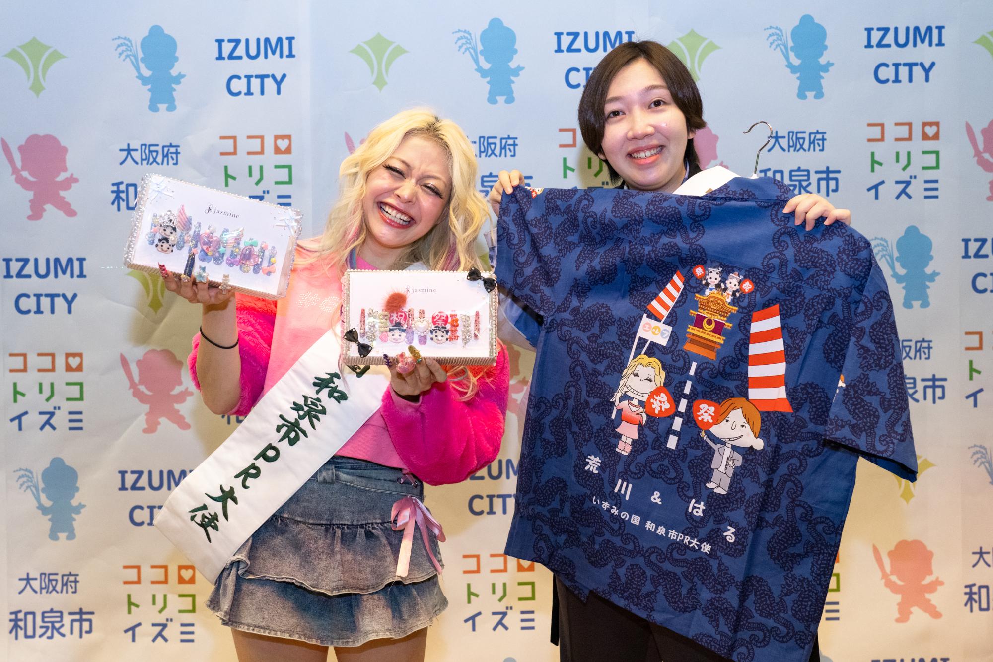 エルフが和泉市からの記念品と写真を撮る様子