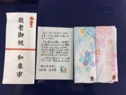 贈呈された敬老祝品の手拭ガーゼと市長からの添え状、熨斗紙を並べた写真