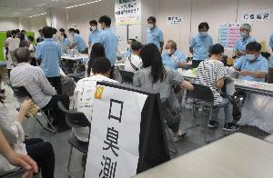 歯科医師会コーナーで色々な口腔検査を受ける来場者たちの写真