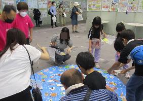 食のコーナーで魚釣りゲームのルールを利用した食品つりに参加する子供たちの写真