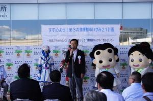 開会式典にてゆるきゃらを背にして挨拶する和泉市長の写真