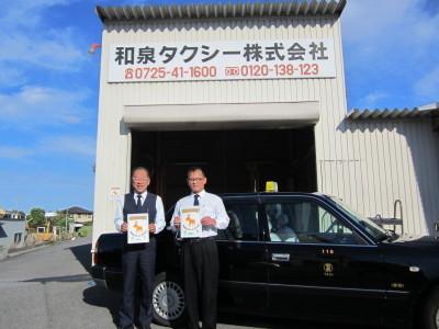 和泉タクシー株式会社の前にてタクシーを背にして並ぶ従業員2人の写真