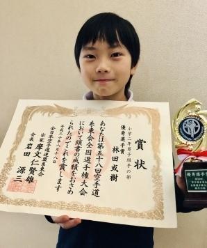 第58回空手道糸東会全国選手権大会にて獲得した優秀選手の賞状とトロフィーを持つ林田或樹さんの写真