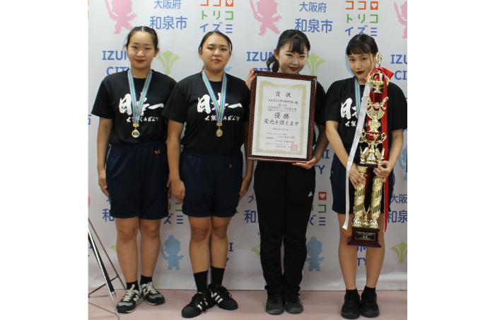 優勝メダルを首にかけ、トロフィーと賞状を持って記念撮影をする久米田高校ダンス部の皆さんの写真