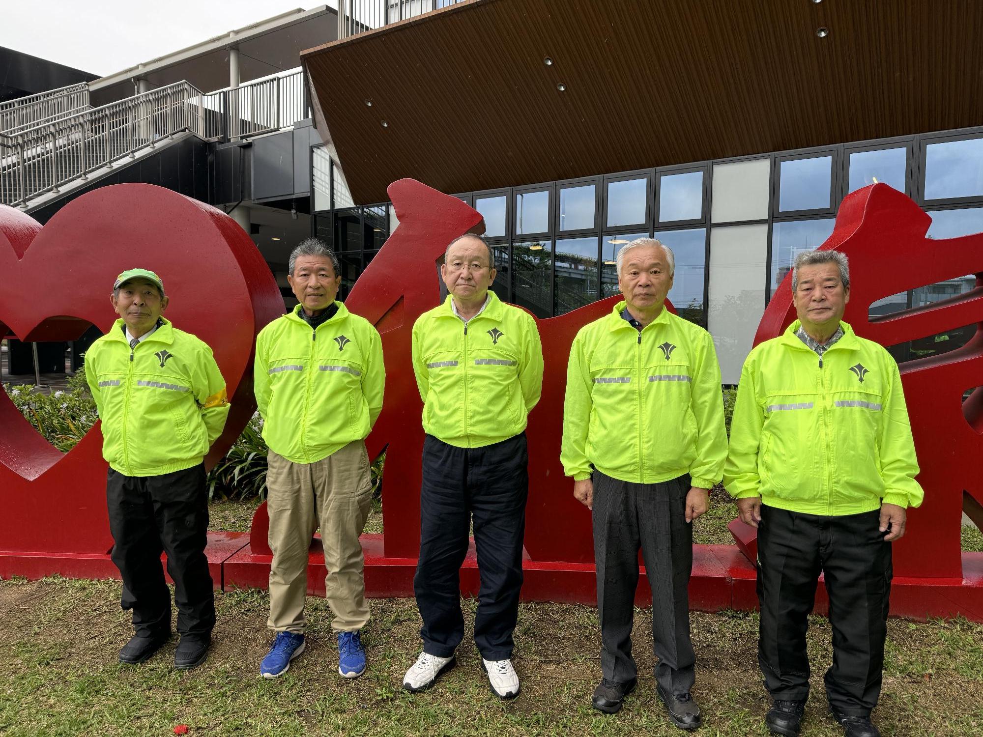 スクールガードリーダーの男性5人がバイクにまたがり横一列に並んでいる写真
