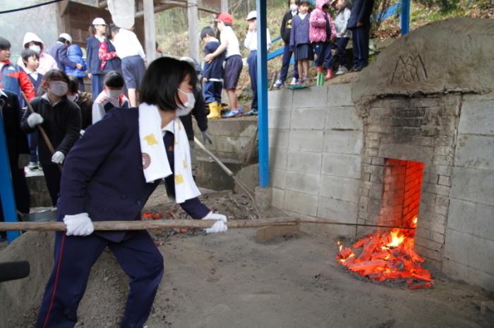 和泉市立南横山小学校の女子生徒が炭焼き体験を行っている様子の写真